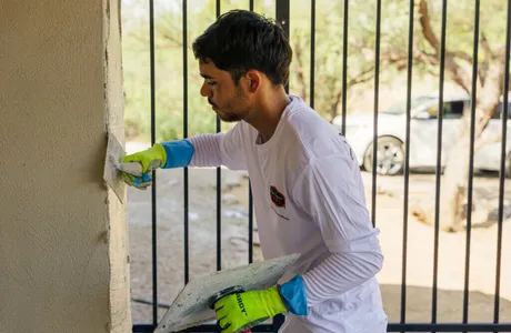 Crew smoothing freshly applied stucco